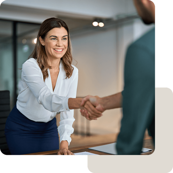 Vertrauensvolles Beratungsgespräch mit Handschlag wischen einer Frau im Business-Outfit und einem Mann im Anzug.